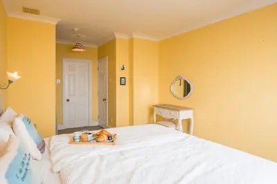 a bedroom with yellow walls and a bed with a cat on it at Orlando, Aldeburgh in Aldeburgh