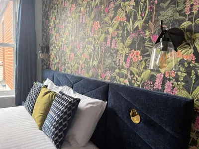 a bedroom with a bed with a floral wallpaper at Sarah Hotel in Harwich