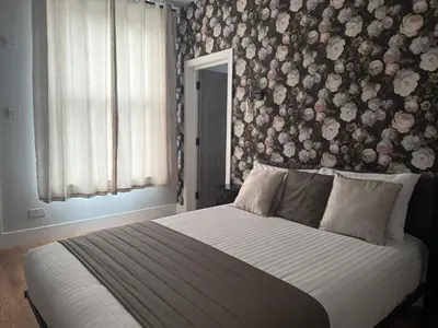 a bedroom with a bed with a floral wall at Sarah Hotel in Harwich