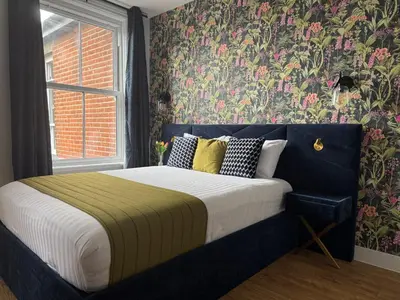 a bedroom with a large bed with floral wallpaper at Sarah Hotel in Harwich