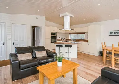 a living room with a black leather couch and a table at Warren Lodges in Little Baddow