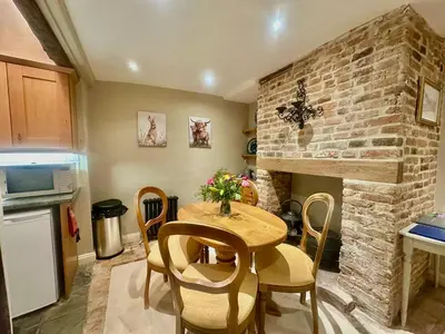 a kitchen with a table and a brick wall at Manor Cottage in Cavendish