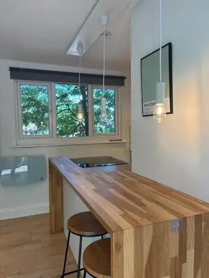 a kitchen with a wooden counter and two stools at Self-contained studio with patio in Ware
