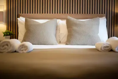 a bed with white pillows and towels on it at Pass the Keys Stylish Riverside Apartment with Free Parking in Cambridge