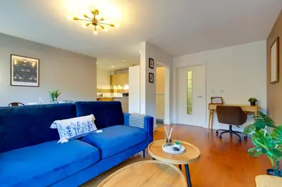 a living room with a blue couch and a table at Pass the Keys Stylish Riverside Apartment with Free Parking in Cambridge