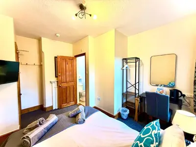 a bedroom with a bed and a mirror and a tv at Coastal Lodge in Leiston
