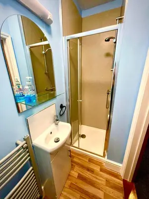 a bathroom with a shower and a sink and a mirror at Coastal Lodge in Leiston