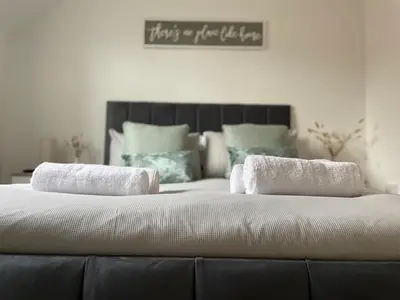 a large bed with two towels on top of it at Iris Cottage 4BR Coastal Retreat in Wenhaston