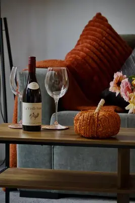 a bottle of wine and a glass on a table at Iris Cottage 4BR Coastal Retreat in Wenhaston