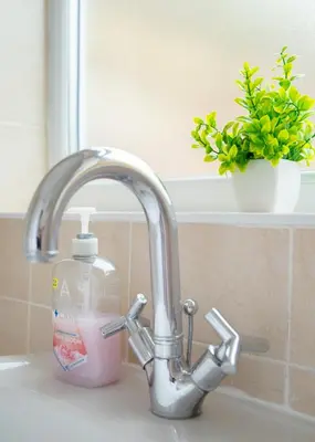 a sink with a bottle of detergent next to a faucet at Stylish central location 3 bedroom house in Ely
