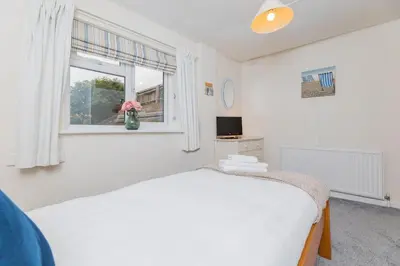 a white bedroom with a bed and a window at Top Step Cottage in Aldeburgh