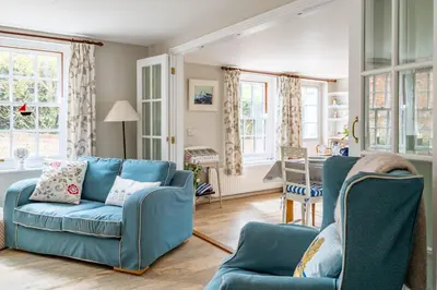 a living room with a blue couch and two chairs at Sanderlings 4 in Aldeburgh