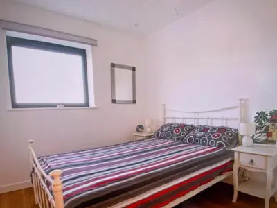 a bedroom with a bed with a striped blanket and a window at Admirals in Shotley Gate