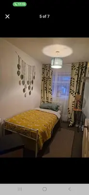 a bedroom with a bed with a yellow comforter and a window at The Green Box in Great Clacton