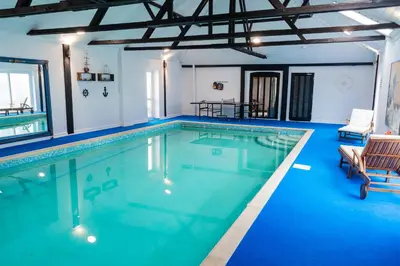 a large swimming pool with blue water at 3 Bed Country House with Pool and Sauna in Tibenham