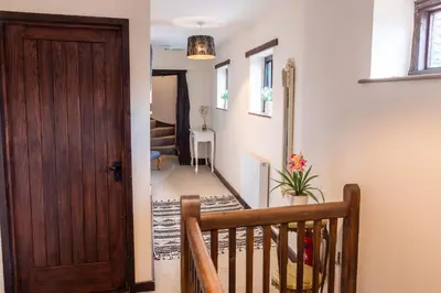 a hallway with a wooden door and a staircase at 3 Bed Country House with Pool and Sauna in Tibenham
