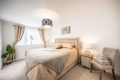 a bedroom with a bed and a chair and a window at A Superb 5BR House near SZC in Leiston