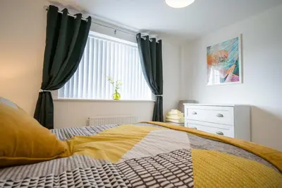 a bedroom with a bed and a window with curtains at A Superb 5BR House near SZC in Leiston