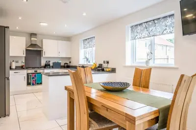 a kitchen with a wooden dining table and chairs at A Superb 5BR House near SZC in Leiston
