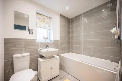 a bathroom with a toilet and a sink and a tub at A Superb 5BR House near SZC in Leiston