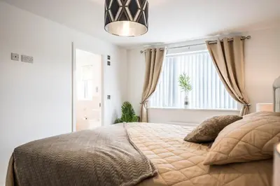 a bedroom with a large bed with a large window at A Superb 5BR House near SZC in Leiston