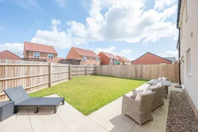a backyard with a fence and a lawn at A Superb 5BR House near SZC in Leiston
