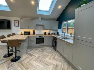 a kitchen with white cabinets and a wooden counter top at Luxury 2 bed new-build house near Science & Business parks in Cambridge