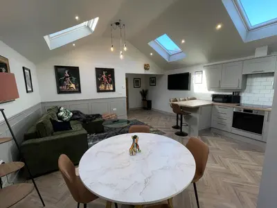 a living room with a table and a kitchen at Luxury 2 bed new-build house near Science & Business parks in Cambridge
