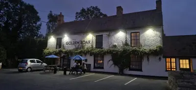 a building with people sitting outside of it at night at The Golden Boar Inn in Freckenham