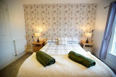 a bedroom with a bed with two green pillows on it at The Golden Boar Inn in Freckenham