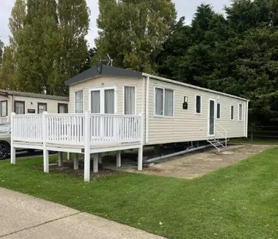 a mobile home with a porch and a white fence at Caravan With Front Decking At Coopers Beach Holiday Park Ref 49080Pa in East Mersea