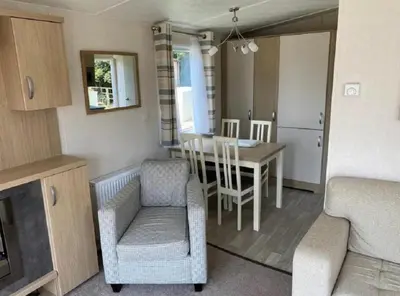 a kitchen and dining room with a table and chairs at Caravan With Front Decking At Coopers Beach Holiday Park Ref 49080Pa in East Mersea