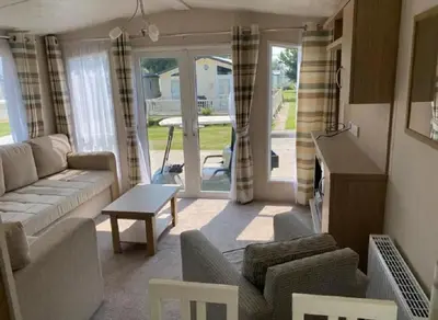 a living room with a couch and a table at Caravan With Front Decking At Coopers Beach Holiday Park Ref 49080Pa in East Mersea
