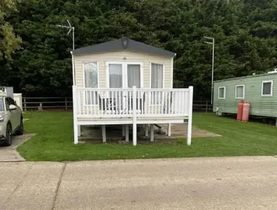 a white house with a porch on the grass at Caravan With Front Decking At Coopers Beach Holiday Park Ref 49080Pa in East Mersea