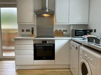 a kitchen with white cabinets and a stove top oven at Iris Group Stay 8-BR Free Parking in Wenhaston