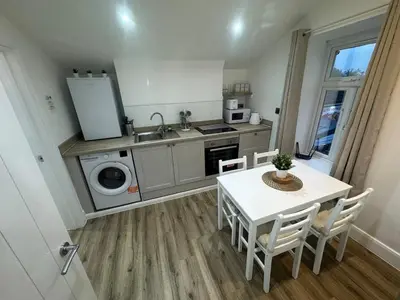 a kitchen with a table and a sink and a stove at Cinema room apartment 1 in Basildon