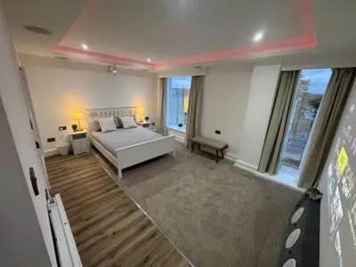 a bedroom with a white bed and a large window at Cinema room apartment 1 in Basildon