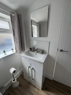 a white bathroom with a sink and a mirror at Cinema room apartment 1 in Basildon