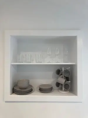 a white shelf with plates and glasses on it at Cinema room apartment 2 in Basildon