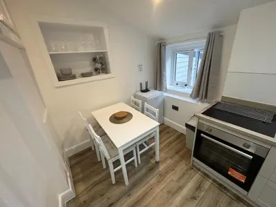 a small kitchen with a white table and a stove at Cinema room apartment 2 in Basildon