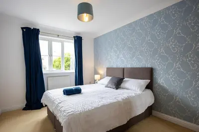a bedroom with a bed with a blue wall at Brook - Sizewell - Contractor Accommodation in Saxmundham