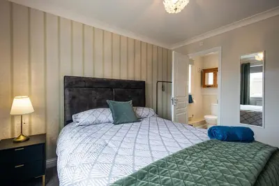 a bedroom with a large bed with a green comforter at Brook - Sizewell - Contractor Accommodation in Saxmundham