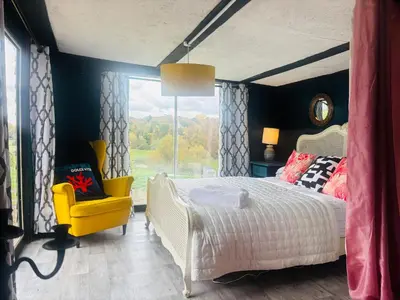 a bedroom with a bed and a yellow chair at Lookout cabin farm stay firepit Hertford in Hertford