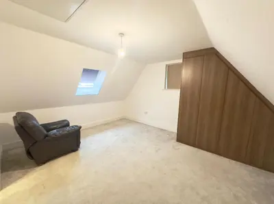 a living room with a chair and a wooden cabinet at Spacious 6-Bed Detached Home in Chigwell in Friern Barnet