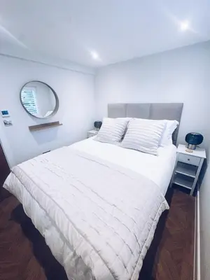 a bedroom with a large white bed with a mirror at Little Dunton Lodges 2 in Brentwood