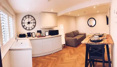 a kitchen and living room with a couch and a clock at Little Dunton Lodges 2 in Brentwood