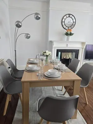 a dining room with a table with chairs and a clock at Coastal Comfort in Leigh Ideal for Work & Leisure in Southend-on-Sea