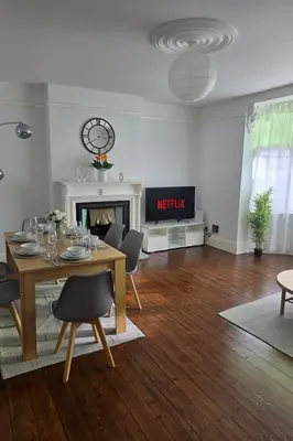 a living room with a table and chairs and a fireplace at Coastal Comfort in Leigh Ideal for Work & Leisure in Southend-on-Sea