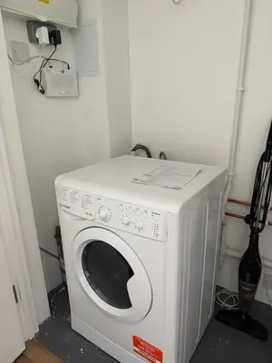 a white washing machine in a corner of a room at Cosy one bedroom flat in the heart of Chelmsford in Chelmsford