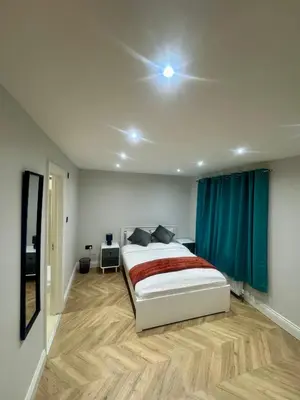 a bedroom with a large bed and a blue curtain at Richard guest house in Roydon